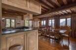 This expansive kitchen and dining area is perfect for entertaining, featuring sleek black countertops and a large wooden dining table.