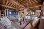 This luxurious living room boasts a stunning wooden beamed ceiling, a large comfortable sectional sofa, and a sleek glass coffee table.