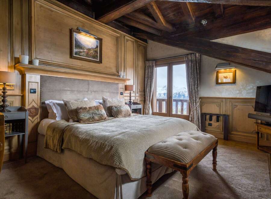 Experience alpine luxury in this exquisitely designed bedroom, featuring wood-paneled walls and exposed beam ceilings.