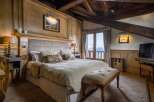 Experience alpine luxury in this exquisitely designed bedroom, featuring wood-paneled walls and exposed beam ceilings.