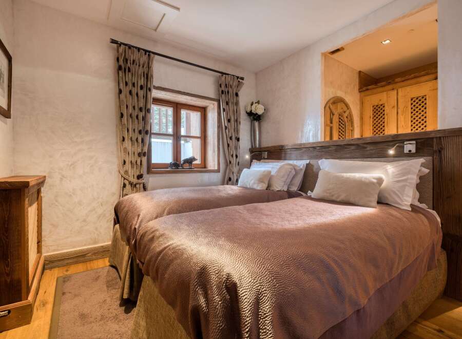 This inviting bedroom features two comfortable twin beds with plush bedding, nestled against a rustic wooden headboard.