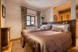 This inviting bedroom features two comfortable twin beds with plush bedding, nestled against a rustic wooden headboard.