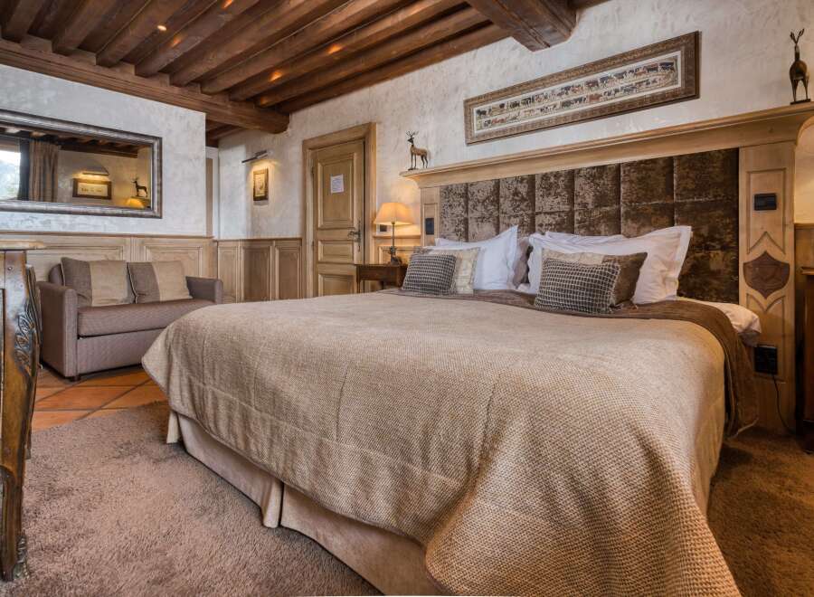 Experience luxury in this charming bedroom with rustic wood beams, a plush queen-size bed, and elegant decor.