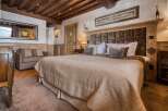Experience luxury in this charming bedroom with rustic wood beams, a plush queen-size bed, and elegant decor.