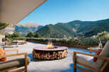 Luxury outdoor living space with a modern fire pit featuring integrated wood storage, perfect for enjoying mountain views.