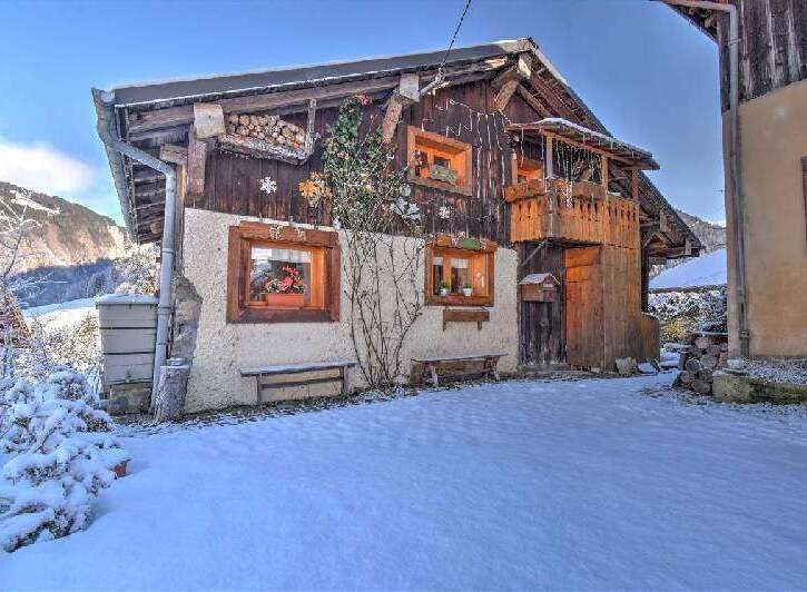 Charming chalet-style home with a wooden facade and cozy balcony, nestled in a snowy landscape.