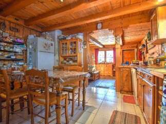 This charming kitchen features wooden beams, cabinets, and walls, creating a warm and inviting atmosphere.