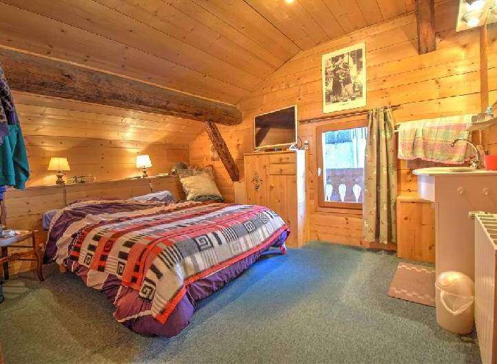 This cozy bedroom features natural wood walls and ceilings, creating a warm and inviting atmosphere.