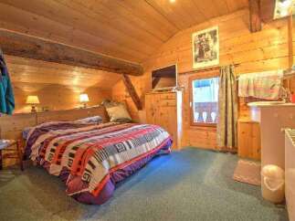 This cozy bedroom features natural wood walls and ceilings, creating a warm and inviting atmosphere.