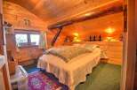 This cozy bedroom features warm wood paneling and exposed beams, creating a rustic and inviting atmosphere.