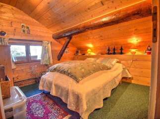 This cozy bedroom features warm wood paneling and exposed beams, creating a rustic and inviting atmosphere.