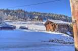 Discover a winter wonderland property featuring a charming wooden cabin nestled amidst snow-covered landscapes and towering trees.
