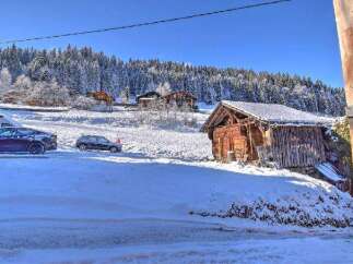 Discover a winter wonderland property featuring a charming wooden cabin nestled amidst snow-covered landscapes and towering trees.