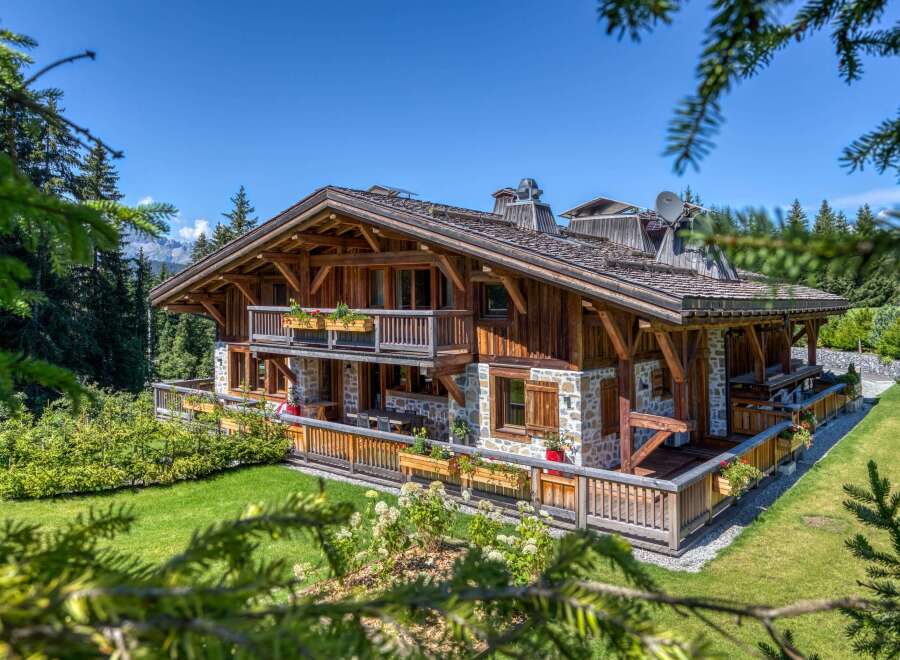 This stunning chalet boasts a harmonious blend of wood and stone architecture, complemented by charming flower boxes adorning the balconies and deck.
