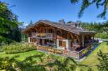 This stunning chalet boasts a harmonious blend of wood and stone architecture, complemented by charming flower boxes adorning the balconies and deck.