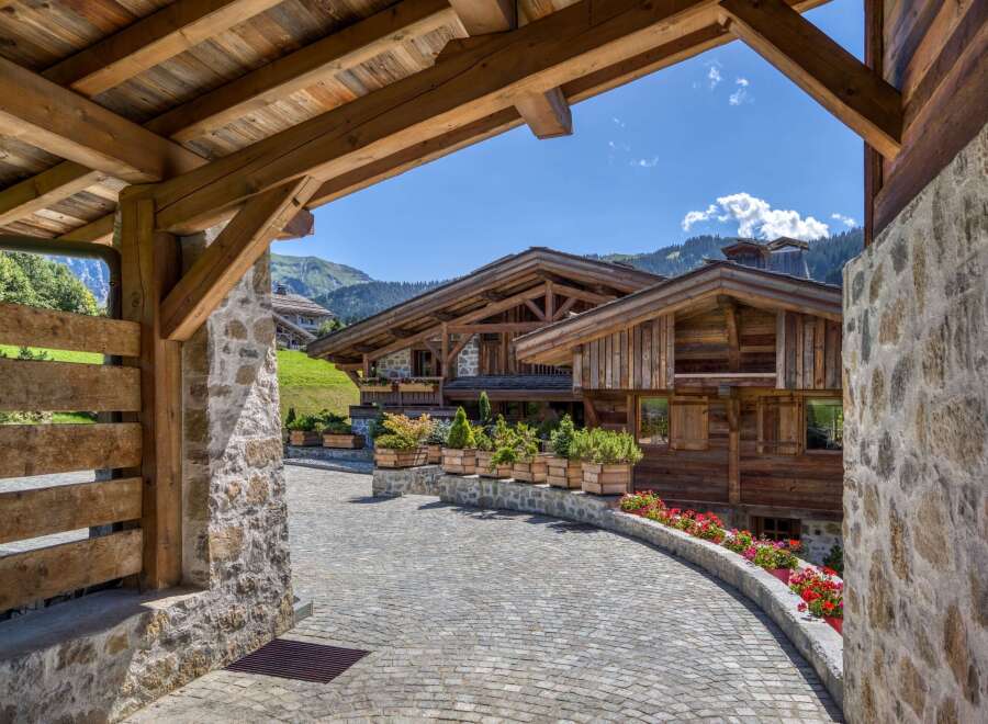 Discover a luxurious chalet nestled in the mountains, featuring stunning wooden architecture and a charming stone pathway.