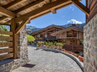 Discover a luxurious chalet nestled in the mountains, featuring stunning wooden architecture and a charming stone pathway.