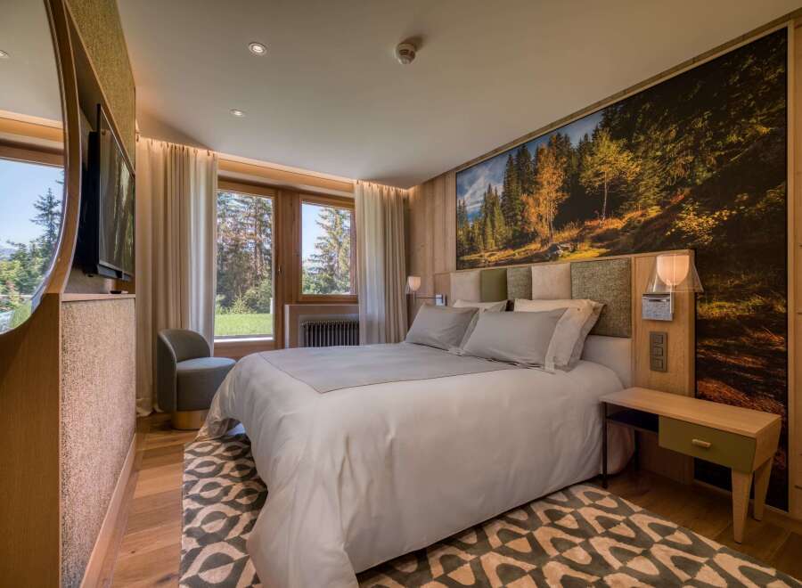 This luxurious bedroom features a king-size bed with plush linens, a stunning forest mural, and natural wood finishes.