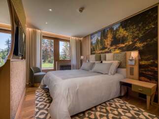 This luxurious bedroom features a king-size bed with plush linens, a stunning forest mural, and natural wood finishes.