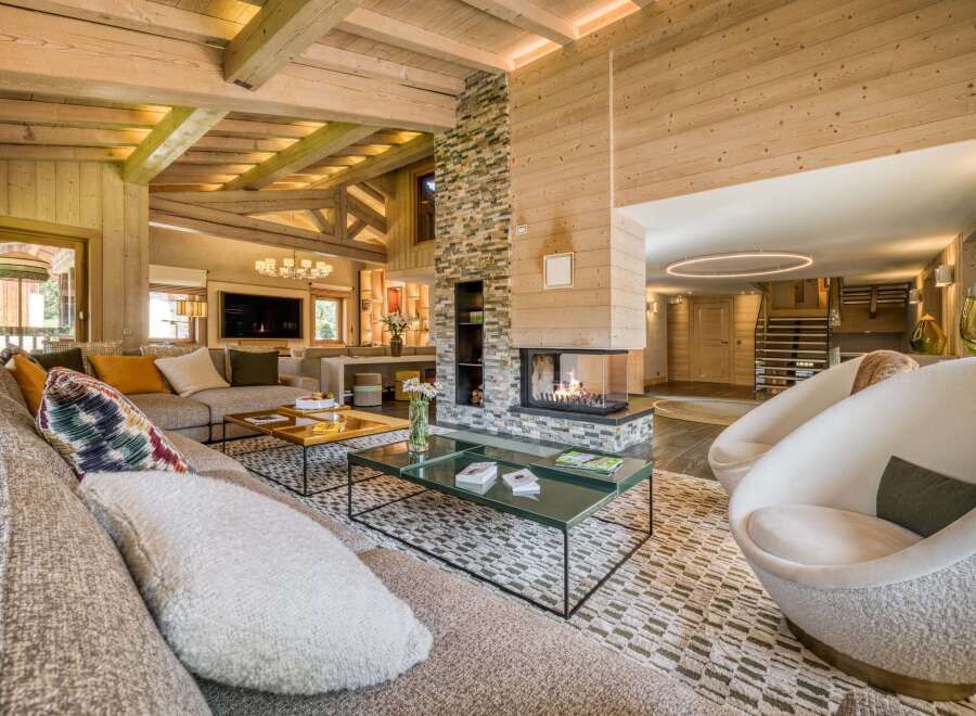 This grand living room boasts natural wood finishes, a stone fireplace, and plush seating.