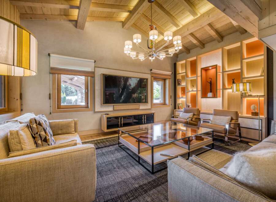 This luxurious living room features a stunning wood-beamed ceiling, a modern chandelier, and a stylish entertainment center.