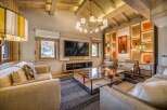 This luxurious living room features a stunning wood-beamed ceiling, a modern chandelier, and a stylish entertainment center.