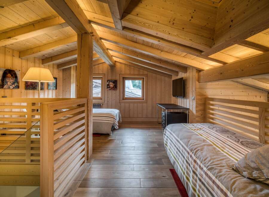 Discover this charming attic bedroom, a cozy retreat featuring natural wood paneling on the walls, ceiling, and floor for a warm, rustic ambiance.