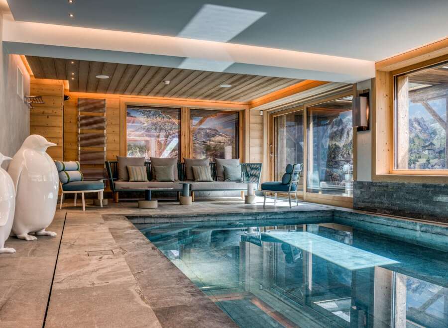 This stunning property boasts an indoor pool with seamless transition to a cozy seating area.