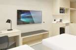 This modern studio apartment features a sleek design, with built-in storage, a kitchenette, and a workspace.