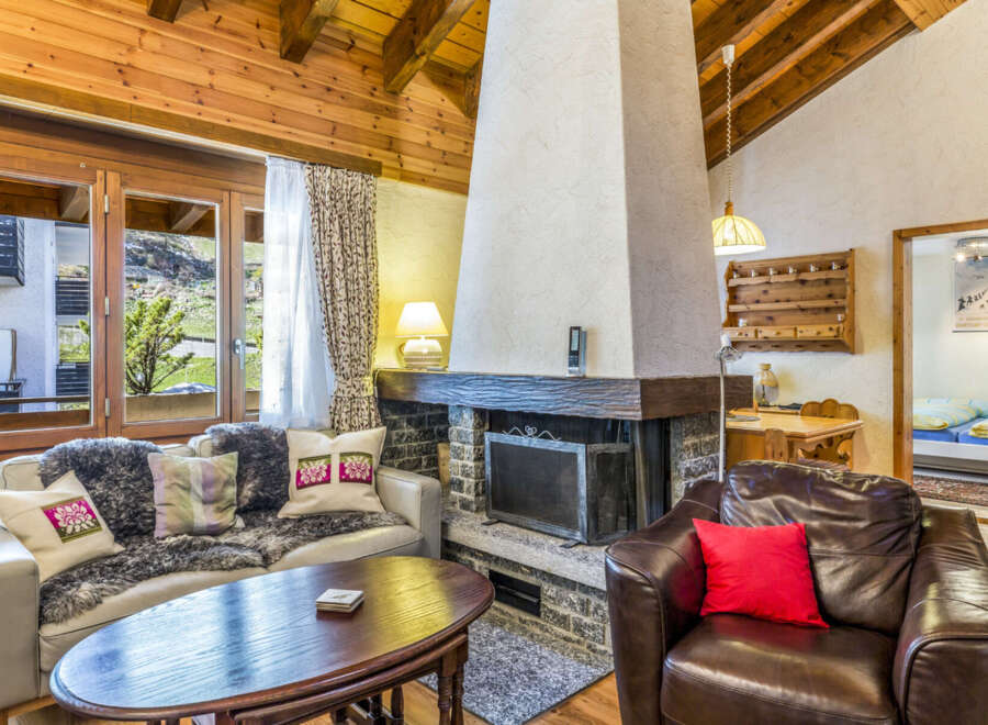 Experience cozy mountain living in this charming chalet featuring a stone fireplace and wood-paneled walls.