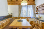 This charming dining area showcases a solid wood table set with a candle centerpiece, surrounded by a cozy wooden bench and heart-backed chairs.