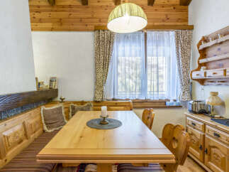 This charming dining area showcases a solid wood table set with a candle centerpiece, surrounded by a cozy wooden bench and heart-backed chairs.