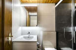 This modern bathroom features a sleek vanity with a white sink, a stylish mirror with integrated lighting, and a toilet with a concealed tank.