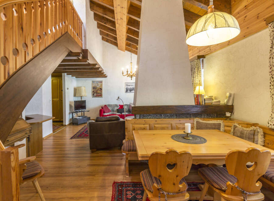Step into this charming chalet-style home, featuring a cozy dining area with wooden furniture and a unique fireplace.