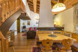 Step into this charming chalet-style home, featuring a cozy dining area with wooden furniture and a unique fireplace.
