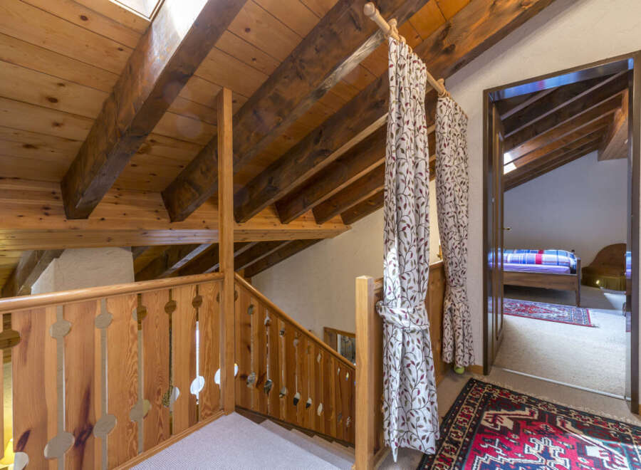 This charming property features a cozy attic space with exposed wooden beams and a unique wooden railing.