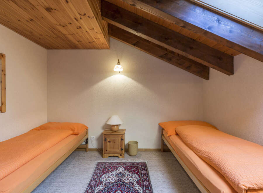 This charming bedroom features two single beds with vibrant orange bedding, perfect for a cozy stay.