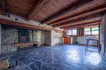 This interior showcases a rustic stone fireplace with a wooden mantel, complemented by a unique floor of irregularly shaped dark tiles.