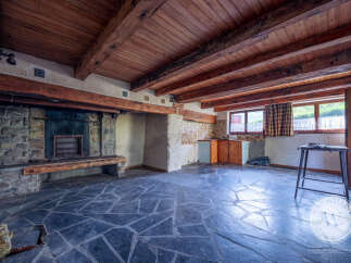 This interior showcases a rustic stone fireplace with a wooden mantel, complemented by a unique floor of irregularly shaped dark tiles.