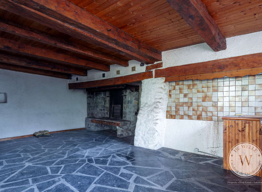 This property features a rustic interior with exposed wooden beams and a stone fireplace, creating a cozy and inviting atmosphere.