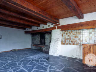 This property features a rustic interior with exposed wooden beams and a stone fireplace, creating a cozy and inviting atmosphere.