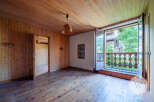 This room features a warm, wood-paneled interior with a charming balcony offering views of lush greenery.