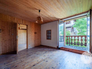 This room features a warm, wood-paneled interior with a charming balcony offering views of lush greenery.