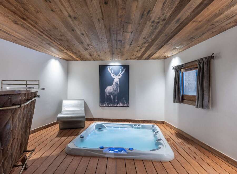 Indulge in the ultimate relaxation in this stunning spa room, featuring a luxurious hot tub, rustic wood accents, and a captivating deer art piece.