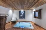 Indulge in the ultimate relaxation in this stunning spa room, featuring a luxurious hot tub, rustic wood accents, and a captivating deer art piece.