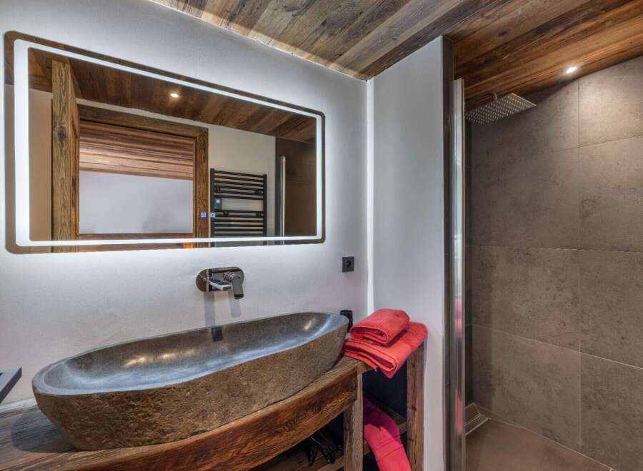 This bathroom features a rustic-chic design with a stone vessel sink atop a reclaimed wood vanity.