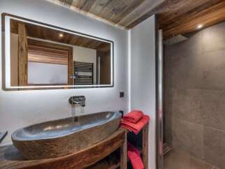 This bathroom features a rustic-chic design with a stone vessel sink atop a reclaimed wood vanity.