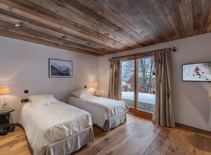 Experience alpine luxury in this inviting bedroom featuring twin beds, rich wood flooring, and a matching wood ceiling.