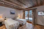 Experience alpine luxury in this inviting bedroom featuring twin beds, rich wood flooring, and a matching wood ceiling.