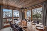 This dining area boasts rustic charm with its wooden ceiling and large windows showcasing a snowy mountain view.